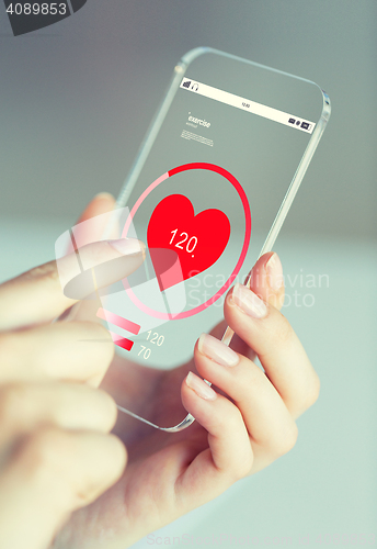 Image of close up of hand with heart rate on smartphone