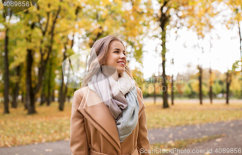 Image of beautiful happy young woman walking in autumn park