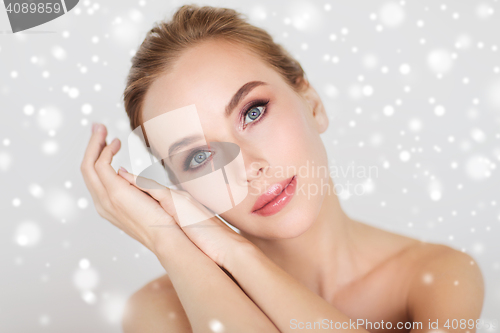 Image of beautiful young woman face and hands over snow