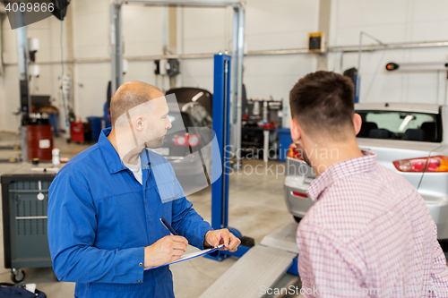 Image of auto mechanic with clipboard and man at car shop