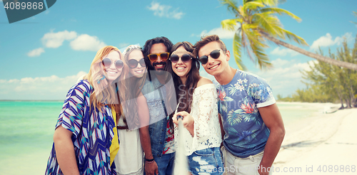 Image of happy hippie friends with selfie stick on beach