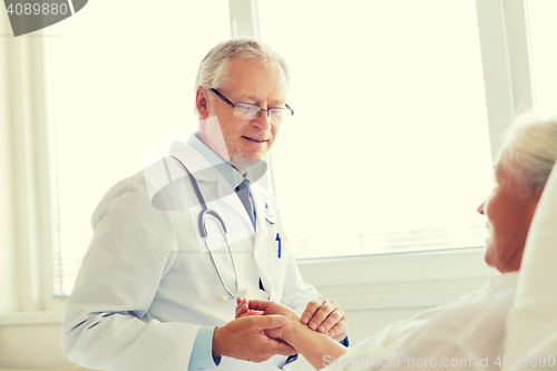 Image of doctor checking senior woman pulse at hospital