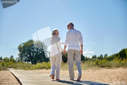 Image of happy senior couple holding hands on summer beach