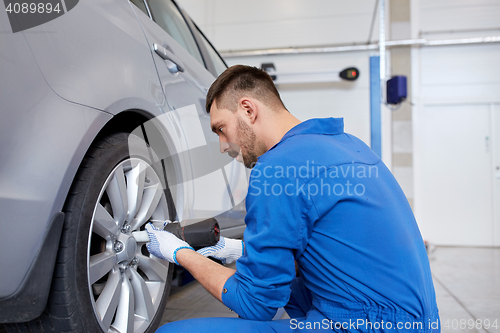 Image of mechanic with screwdriver changing car tire