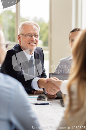 Image of senior businessman making handshake at office