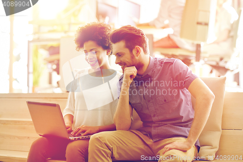 Image of happy creative team with laptop in office