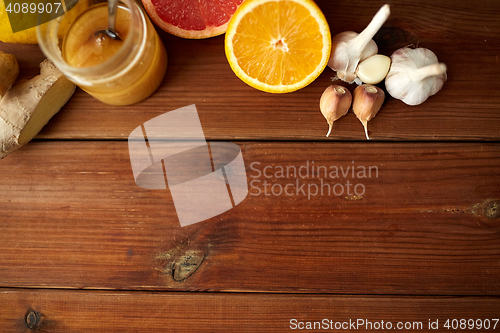 Image of honey, citrus fruits, ginger and garlic on wood