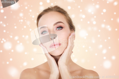 Image of beautiful young woman face and hands over snow