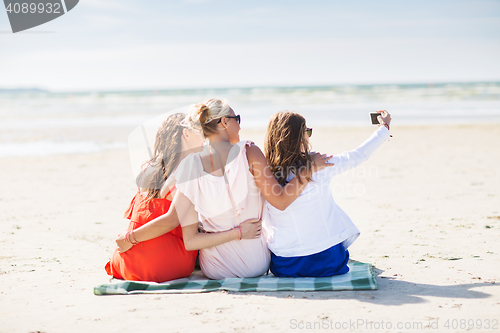 Image of happy women taking selfie by smartphone on beach
