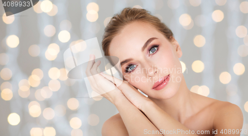 Image of beautiful woman face and hands over lights