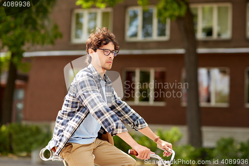 Image of young hipster man with bag riding fixed gear bike