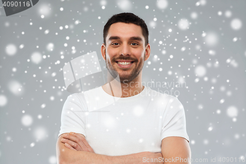 Image of smiling man with crossed arms over snow background