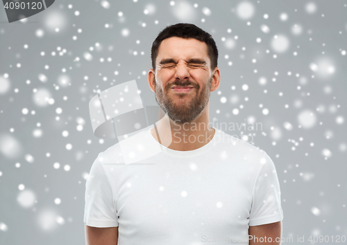 Image of man screwing up his face over snow background