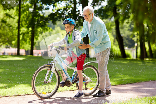 Image of grandfather and boy with bicycle at summer park