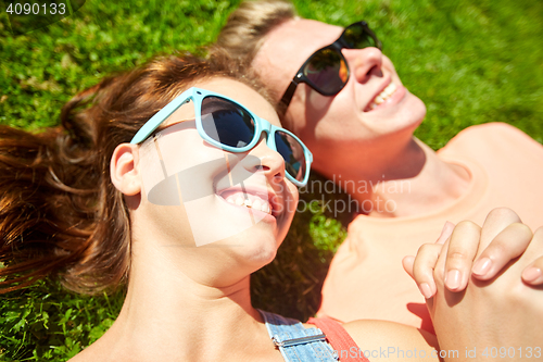 Image of happy teenage couple lying on grass at summer