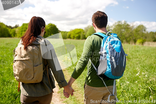 Image of happy couple with backpacks hiking outdoors