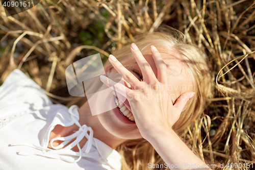 Image of happy young woman lying on cereal field