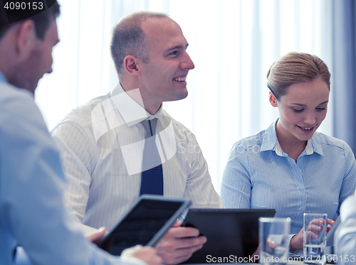 Image of smiling businesspeople with tablet pc in office