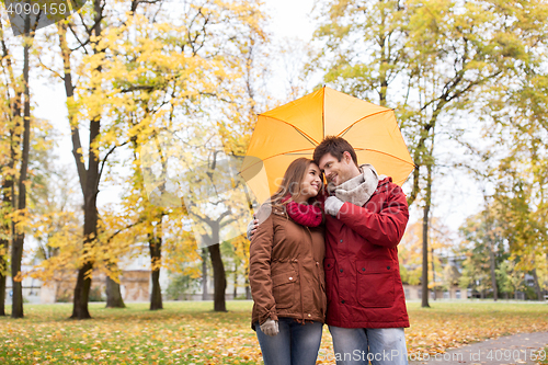 Image of smiling couple with umbrella in autumn park