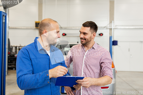 Image of auto mechanic with clipboard and man at car shop