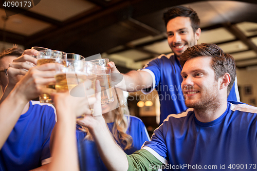 Image of football fans clinking beer glasses at sport bar