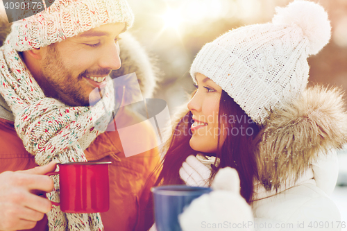 Image of happy couple with tea cups over winter landscape