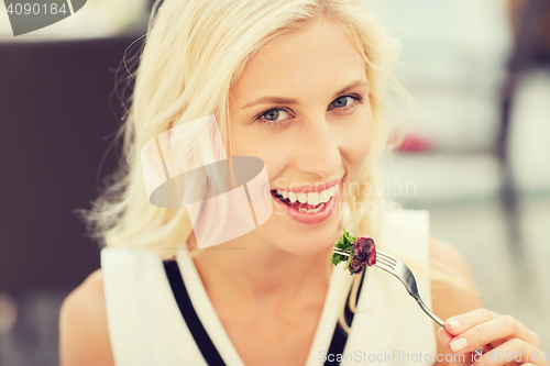Image of happy woman eating dinner at restaurant terrace