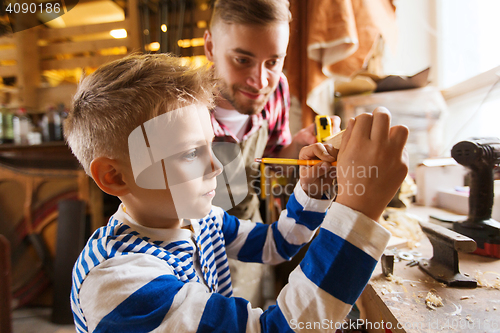 Image of father and son with ruler measure wood at workshop