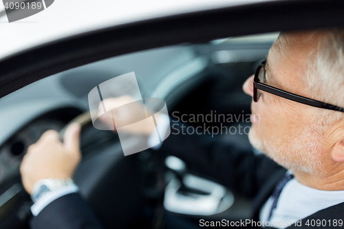 Image of happy senior businessman driving car