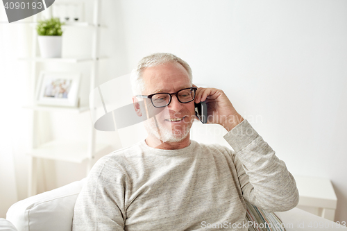 Image of happy senior man calling on smartphone at home