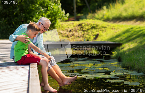 Image of grandfather and grandson sitting on river berth