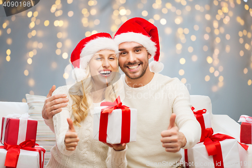 Image of happy couple with christmas gifts and thumbs up