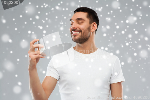 Image of smiling man with male perfume over snow background