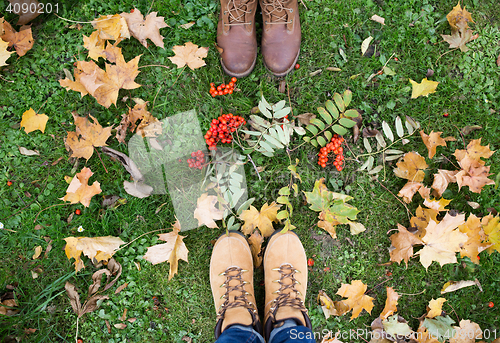 Image of feet in boots with rowanberries and autumn leaves