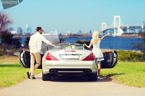 Image of happy man and woman near cabriolet car in tokyo