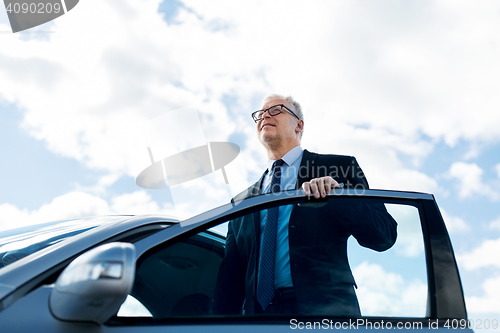 Image of senior businessman getting into car