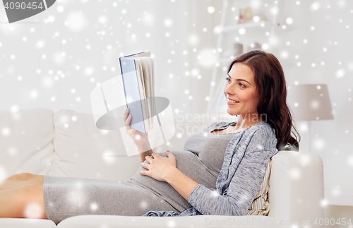 Image of happy pregnant woman reading book at home