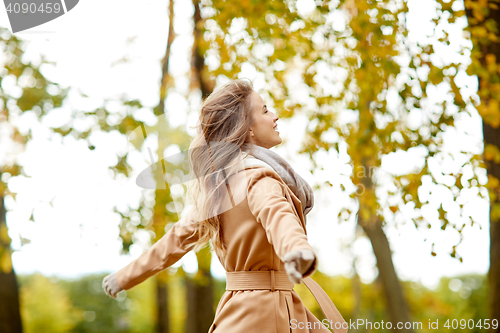 Image of beautiful happy young woman walking in autumn park