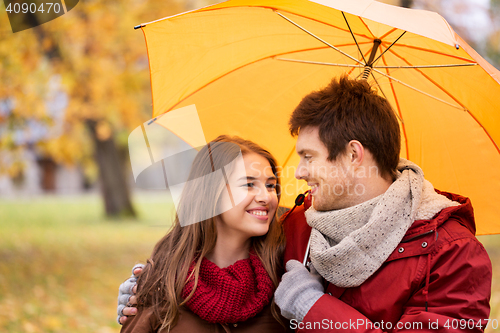 Image of smiling couple with umbrella in autumn park