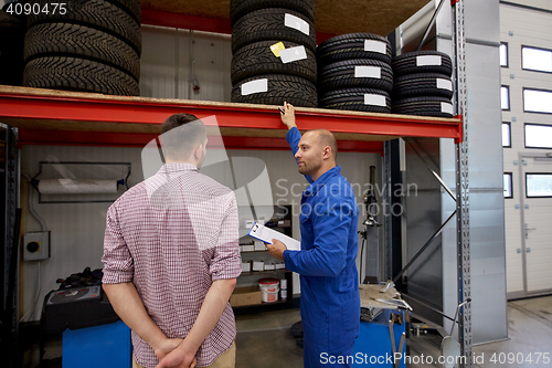 Image of auto mechanic and man with tires at car shop