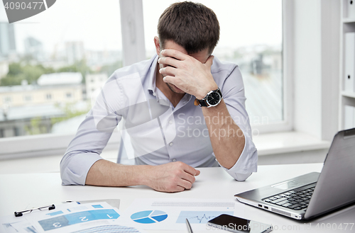 Image of stressed businessman with papers in office