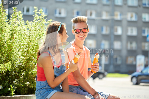 Image of happy teenage couple eating hot dogs in city