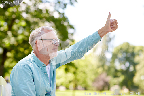 Image of happy senior man showing thumbs up at summer park