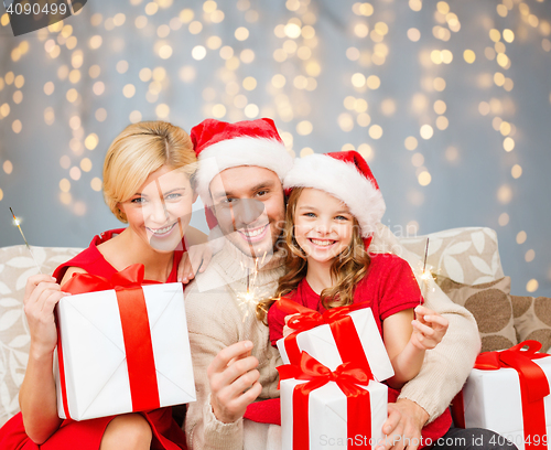 Image of happy family holding gift boxes and sparkles