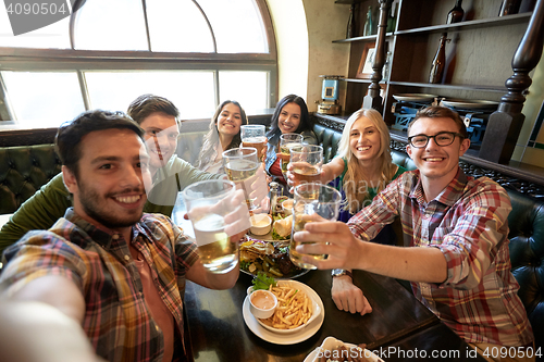 Image of happy friends taking selfie at bar or pub