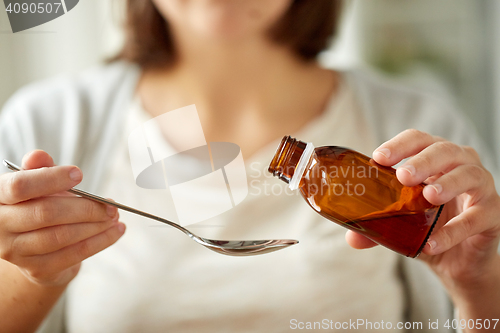 Image of woman pouring medication from bottle to spoon