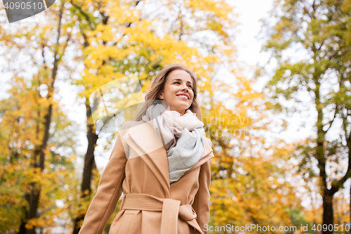 Image of beautiful happy young woman walking in autumn park