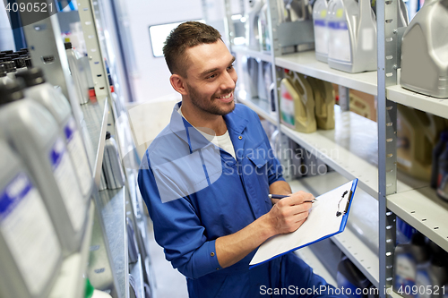 Image of smiling auto mechanic with clipboard at car shop