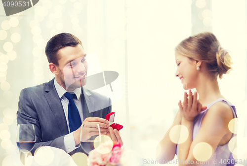 Image of man proposing to his girlfriend at restaurant