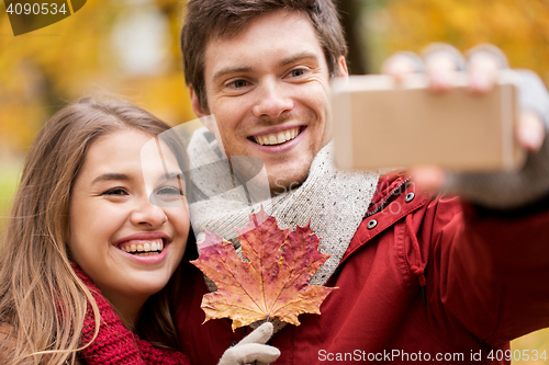 Image of couple taking selfie by smartphone in autumn park
